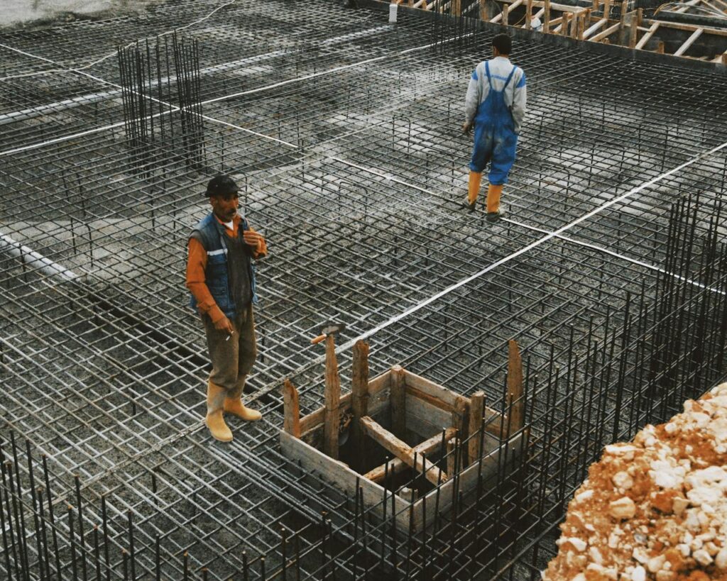 Workers preparing steel reinforcement at a construction site for concrete foundation.