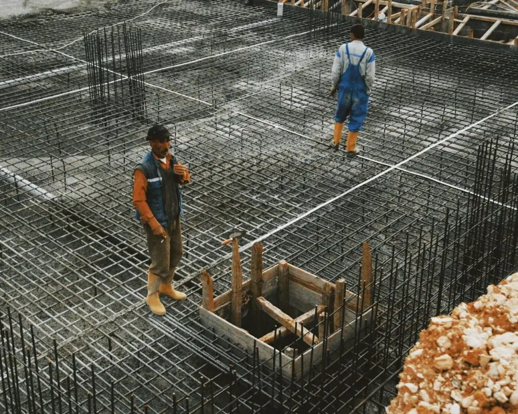 Workers preparing steel reinforcement at a construction site for concrete foundation.